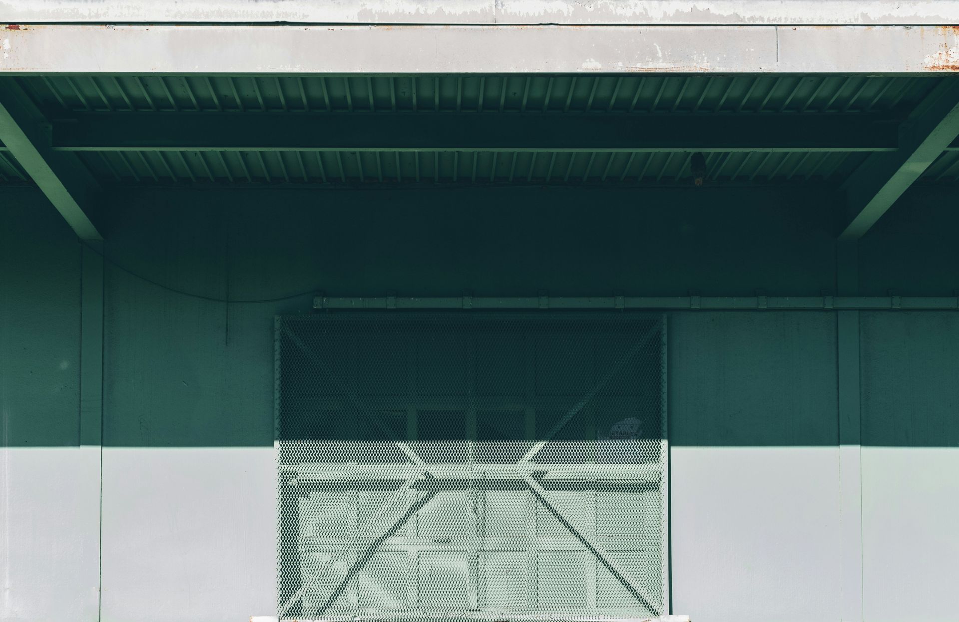 A green and white warehouse with a light green garage door.