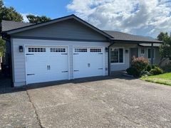 A row of white garage doors on the side of a house