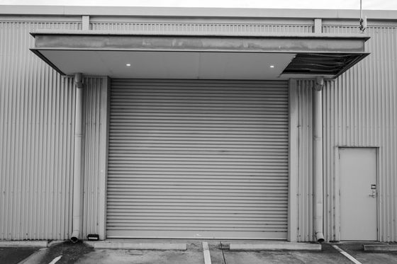 A black and white photo of a building with a garage door.