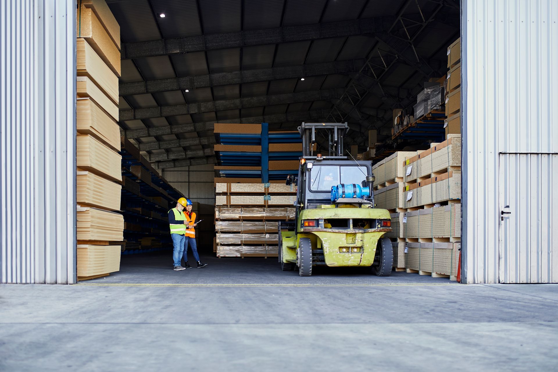 A forklift is loading wood into a warehouse.
