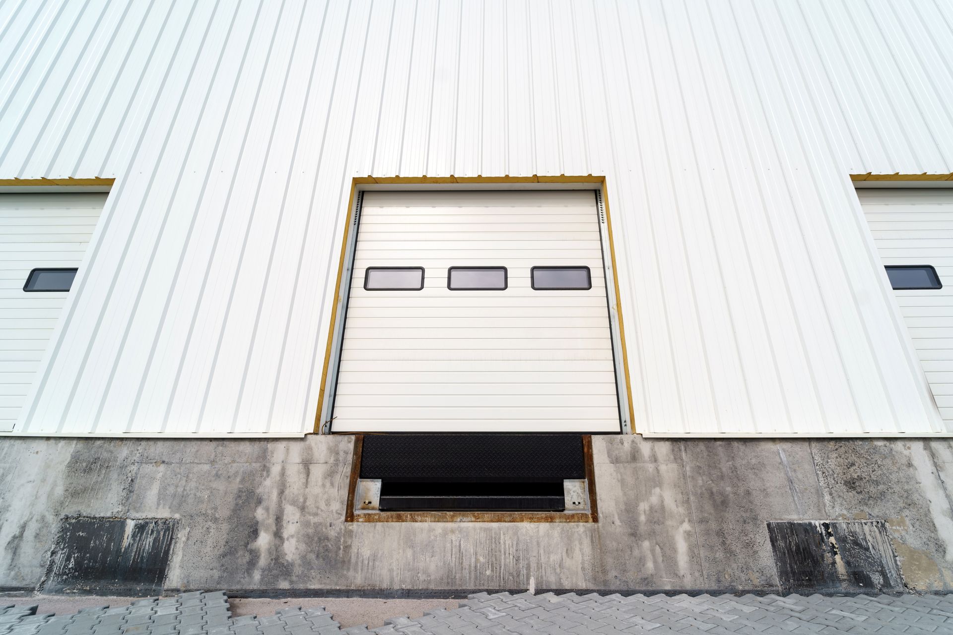A white garage door is open on the side of a building.