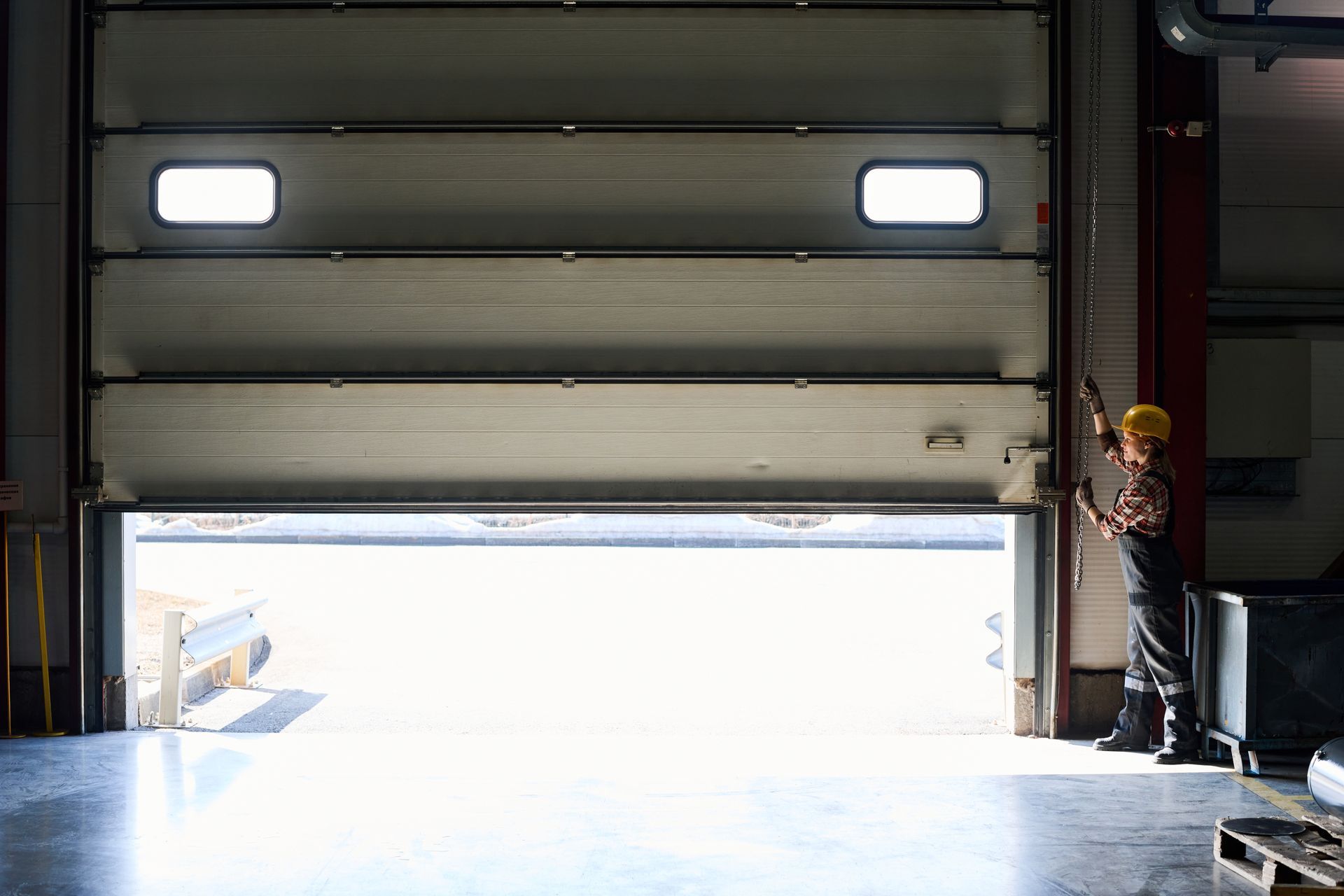 A man is standing in front of an open garage door in a warehouse.