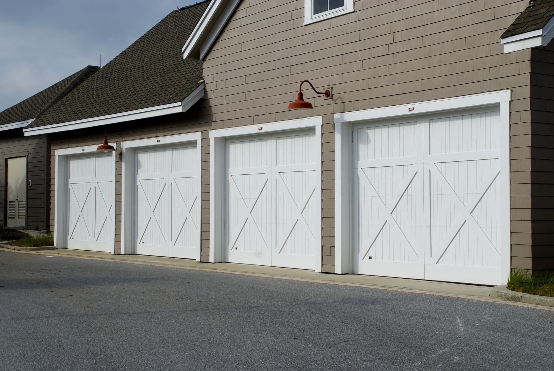 A row of white garage doors on the side of a house