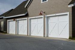 A row of white garage doors on the side of a house