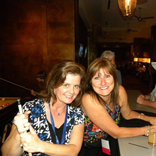 Two women are posing for a picture while sitting at a table