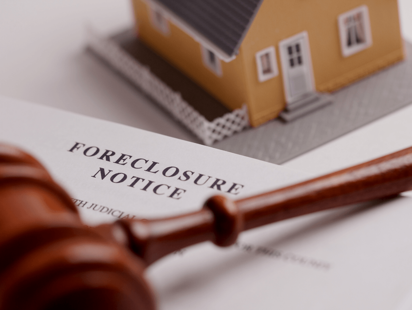 A model house sits on top of a foreclosure notice
