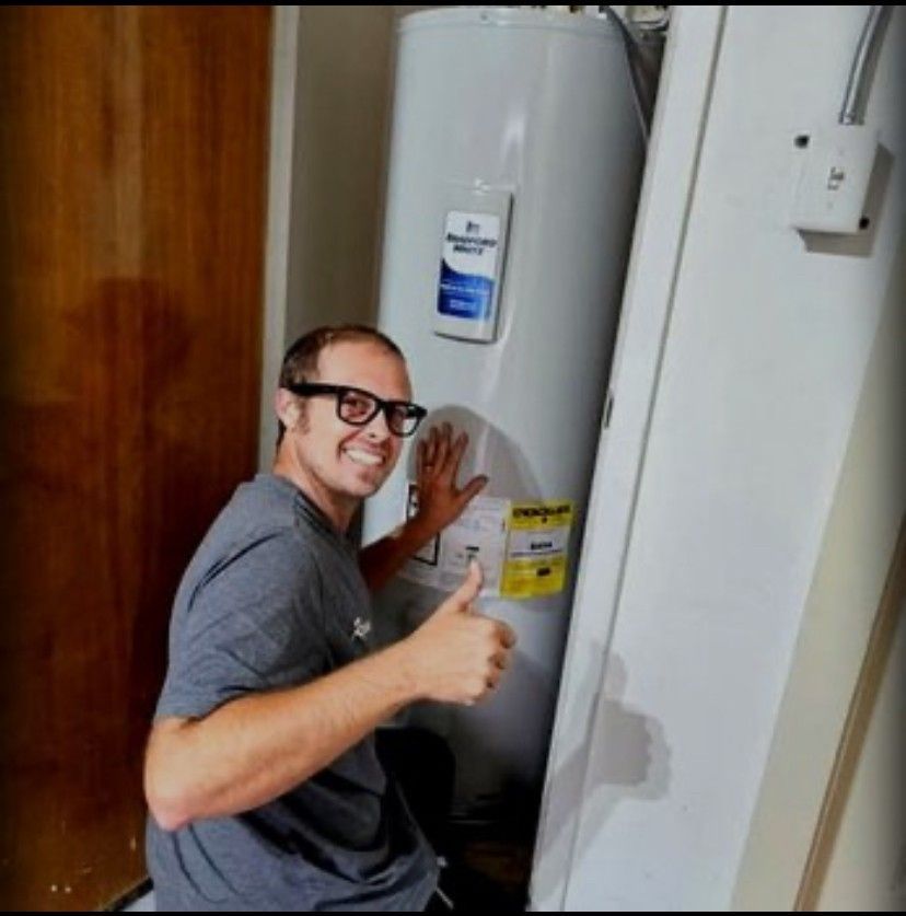 A plumber is kneeling down in a kitchen looking under a sink.
