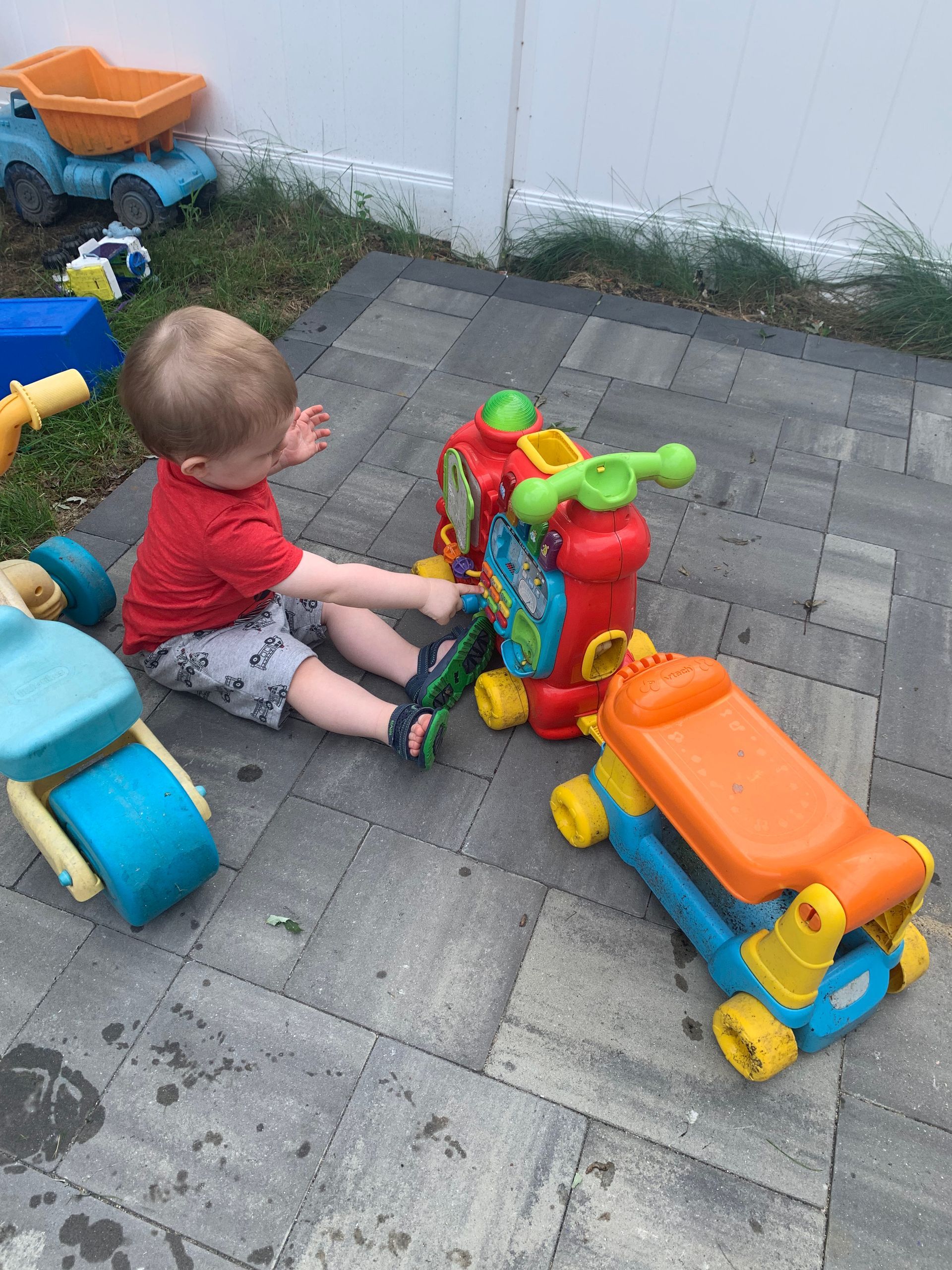 A little boy is sitting on the ground playing with toys.