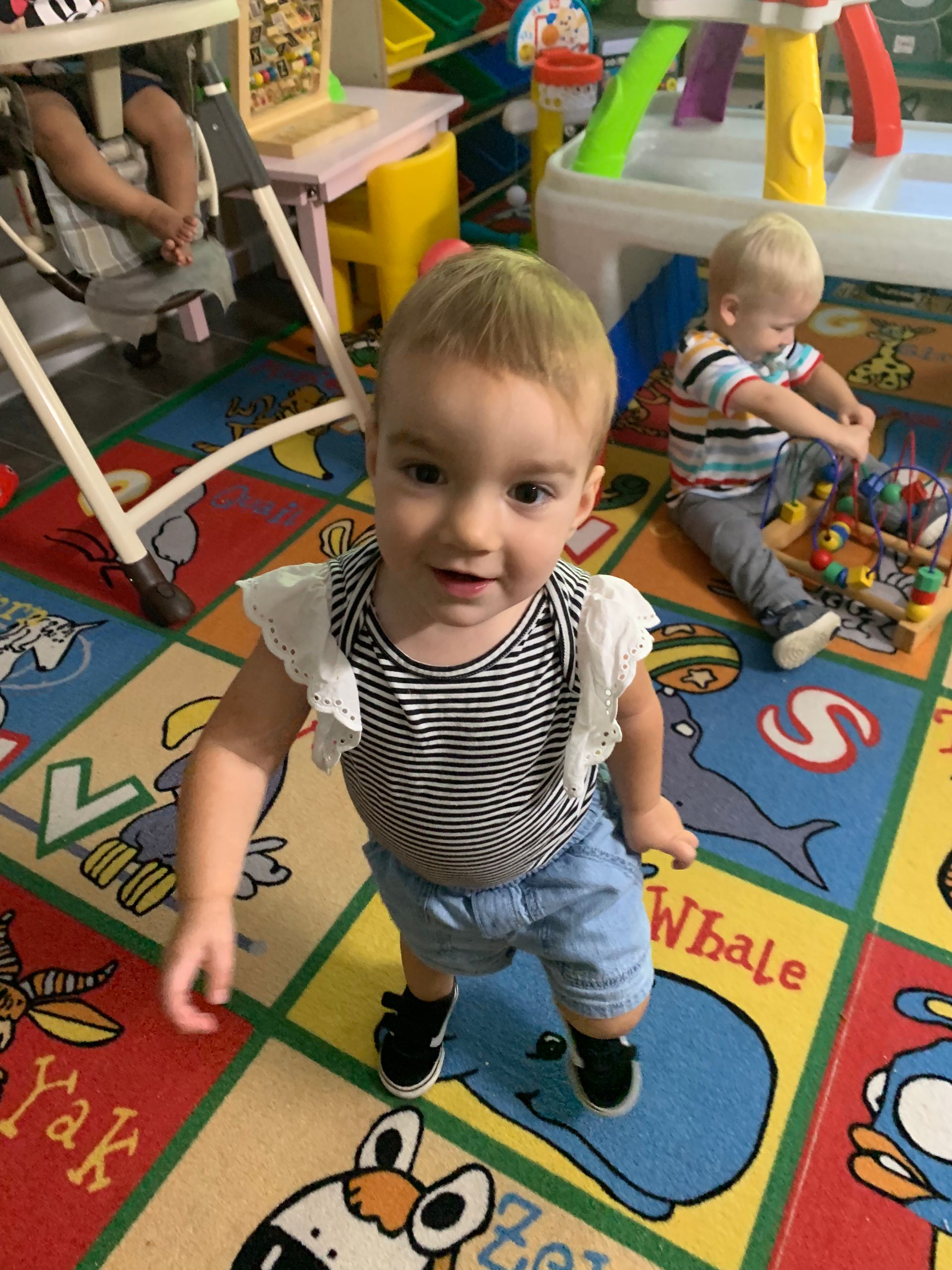 A little girl is standing on a rug that says whale