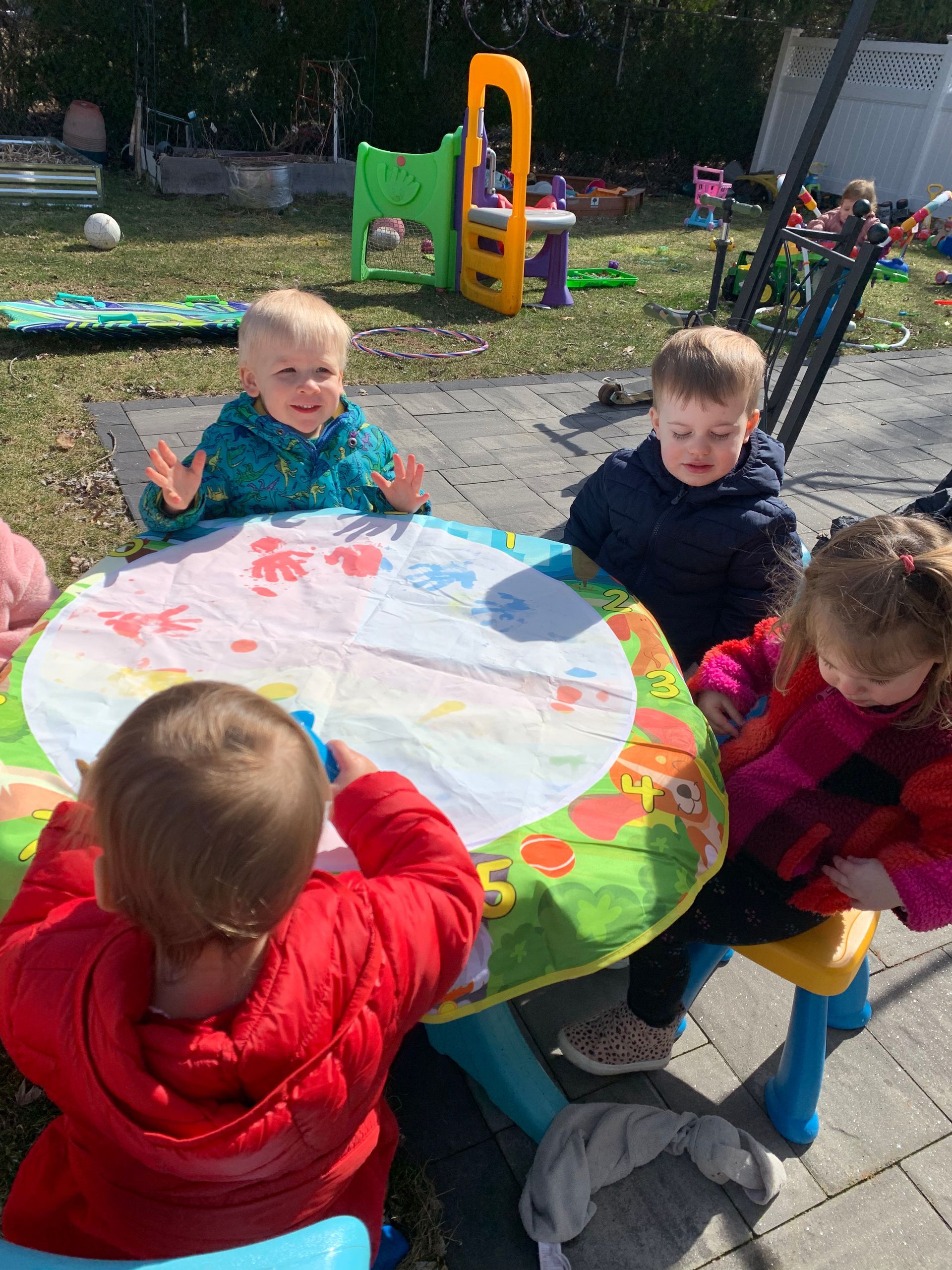 A group of children are sitting at a table outside.