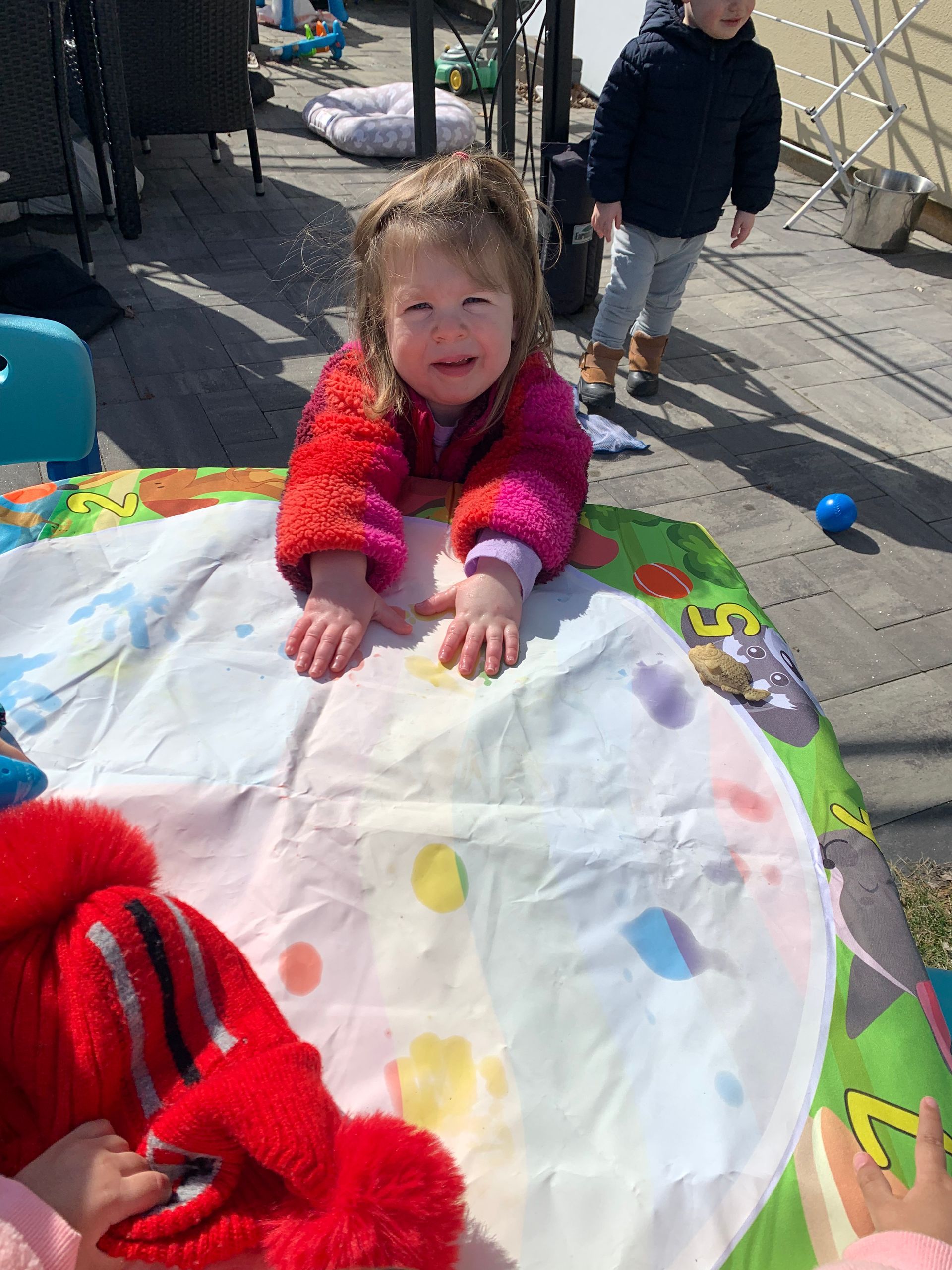 A little girl is laying on a table with a stuffed animal.