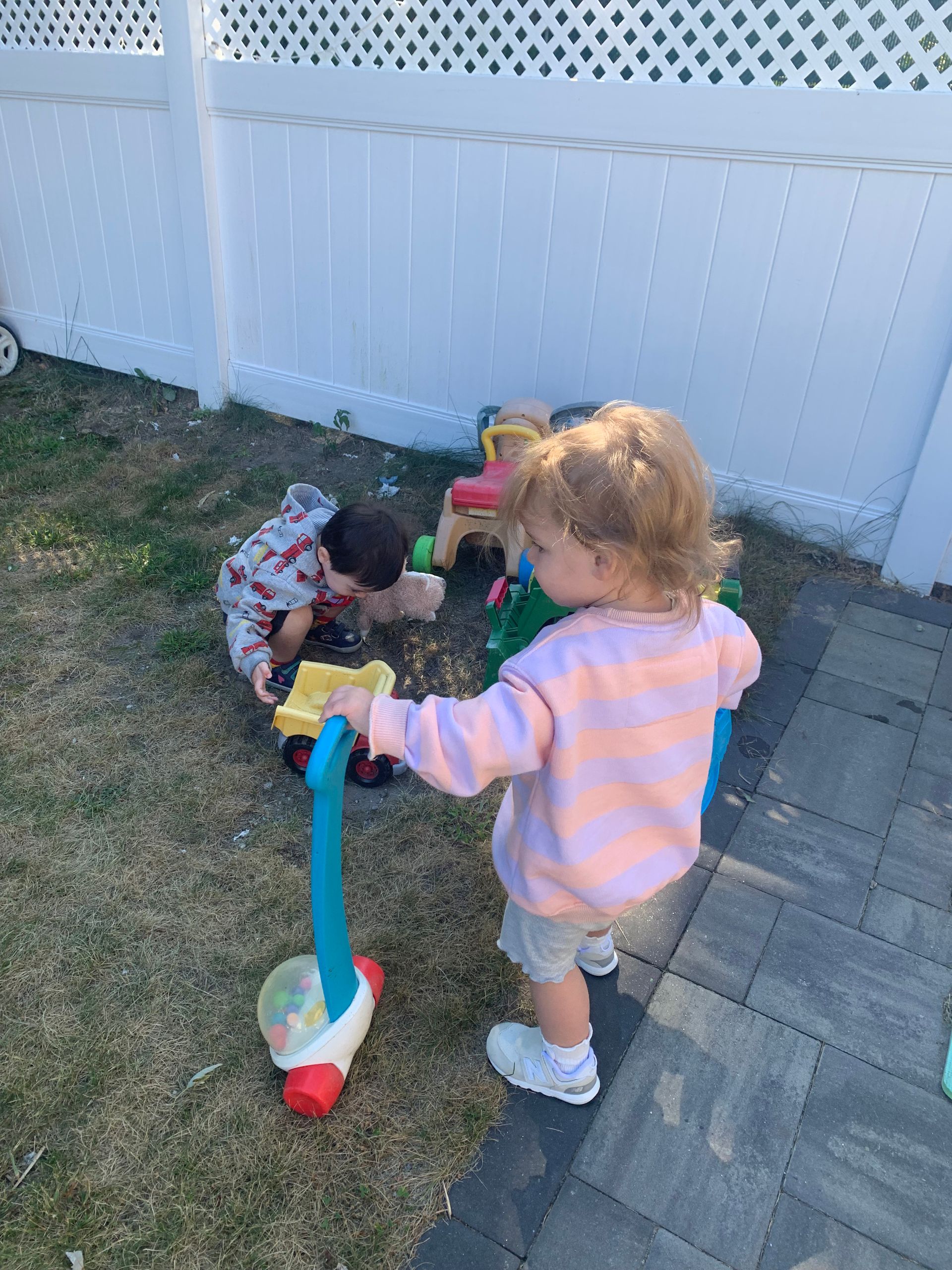 Two children are playing with toys in the backyard.