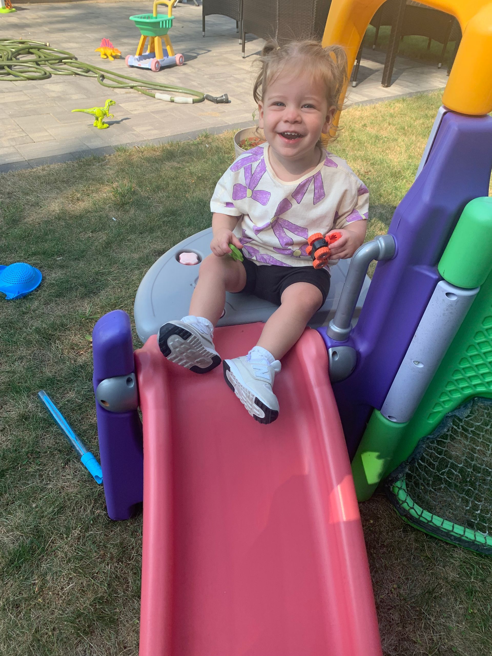 A little girl is sitting on top of a slide.