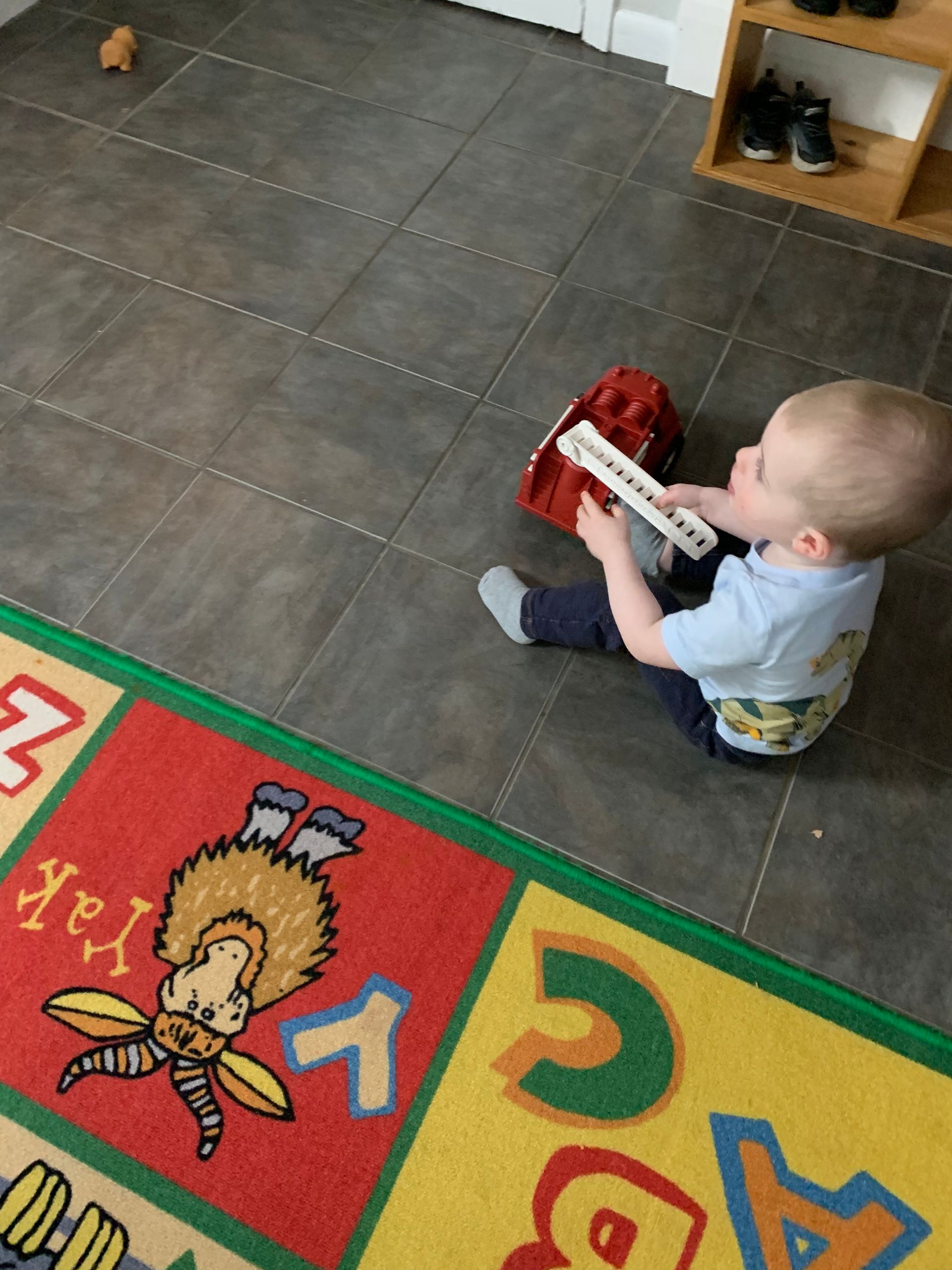 A little boy is sitting on the floor playing with a toy