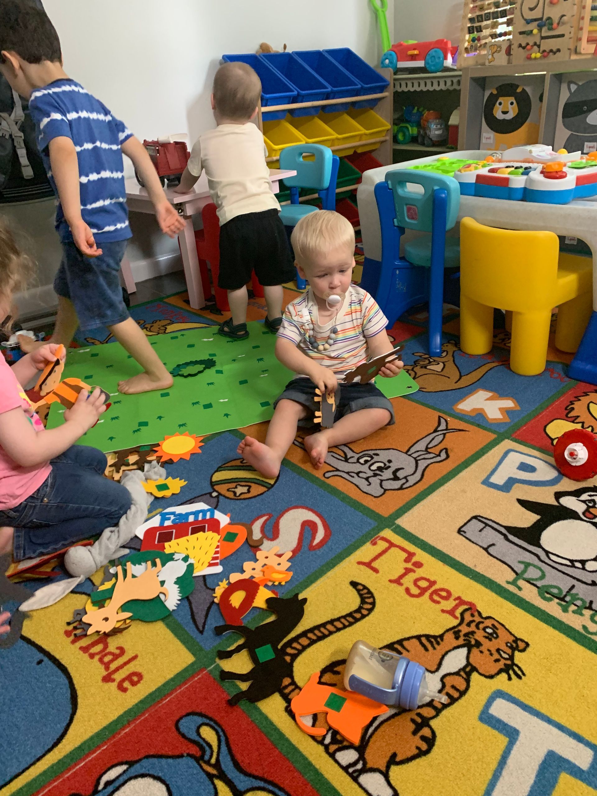 A group of children are playing on a rug that says tiger on it