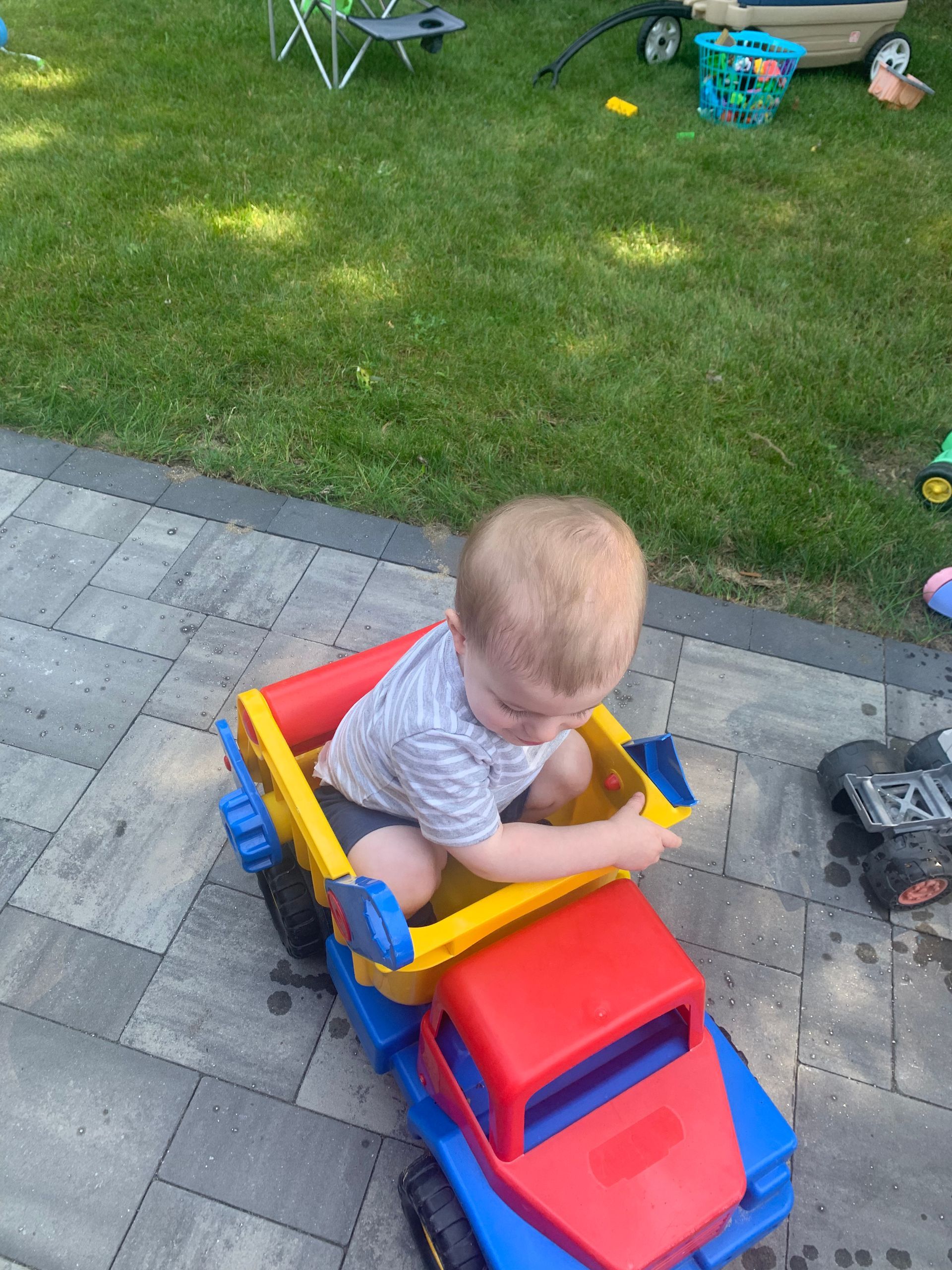 A little boy is sitting on top of a toy truck.