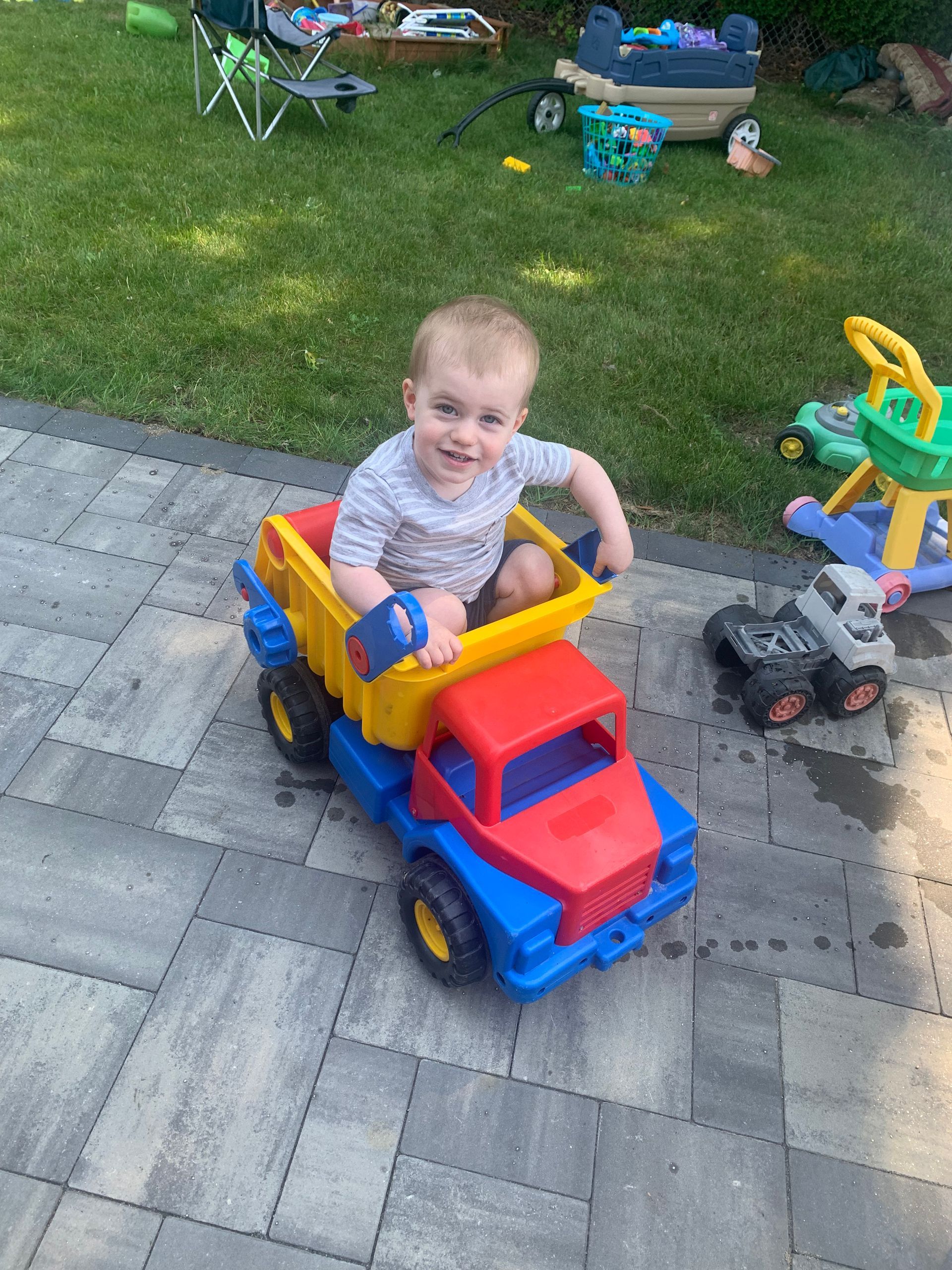 A little boy is sitting in a toy dump truck.