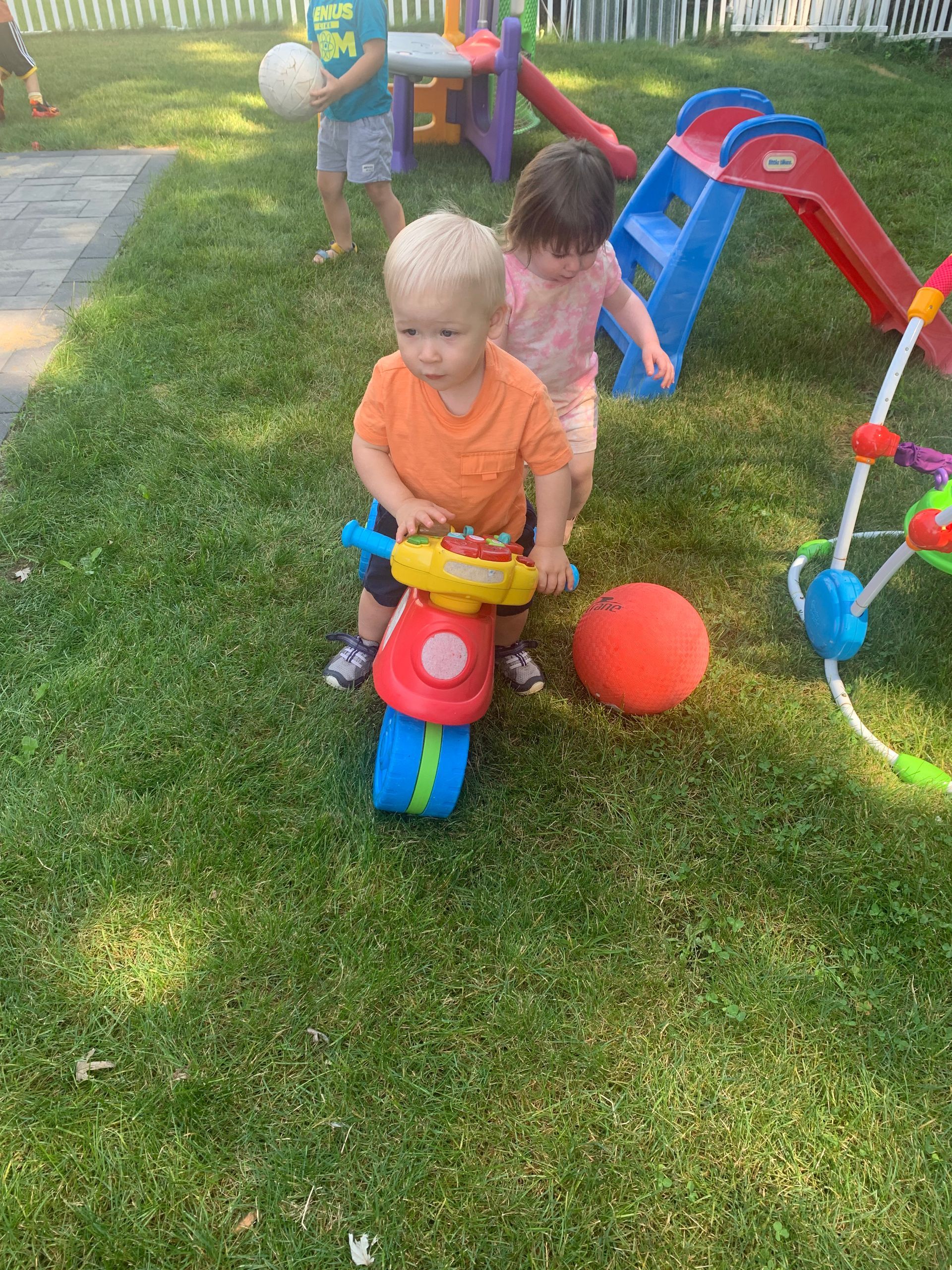 A boy and a girl are playing with toys in the grass.