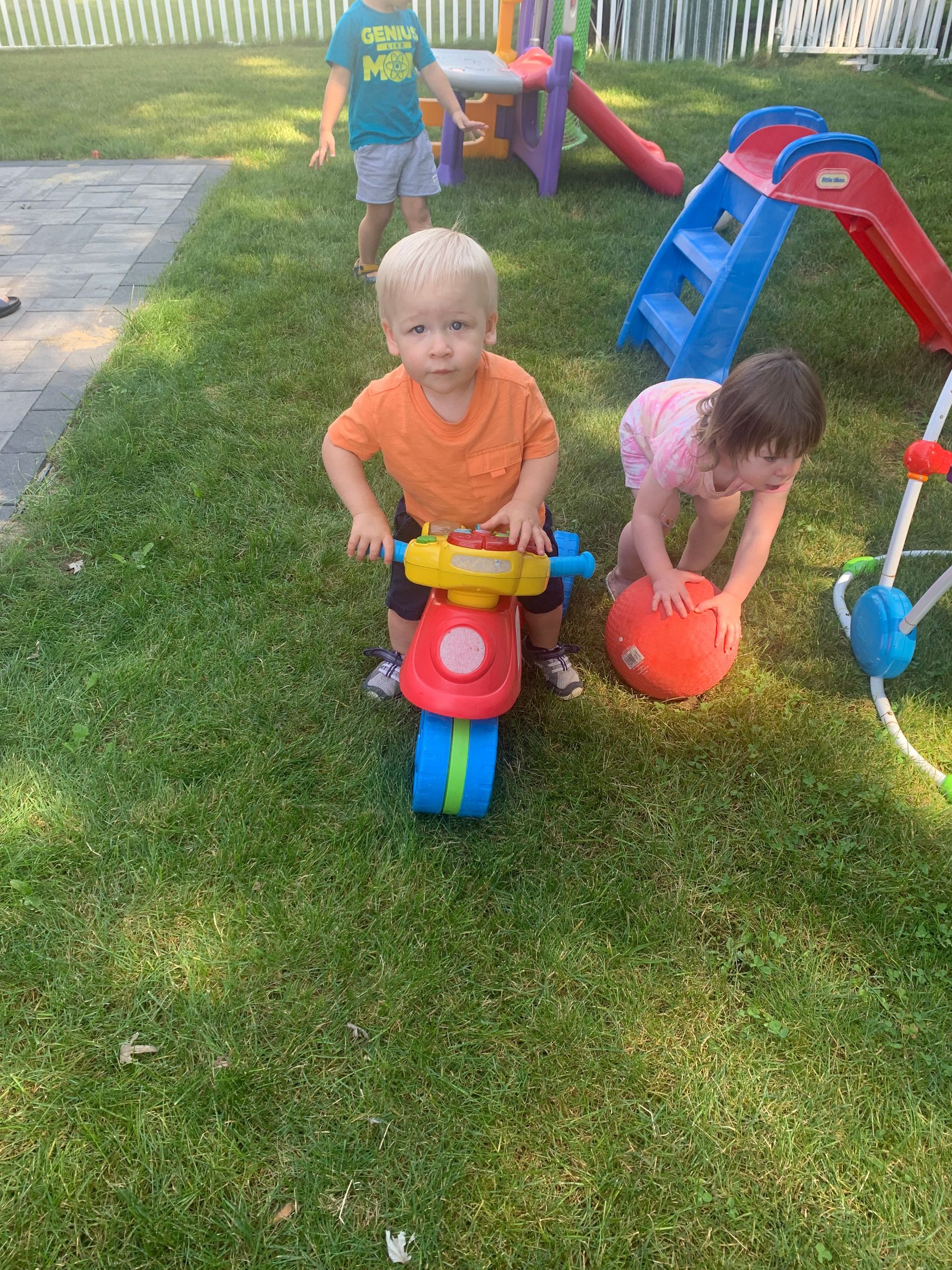 A boy and a girl are playing with toys in the grass.