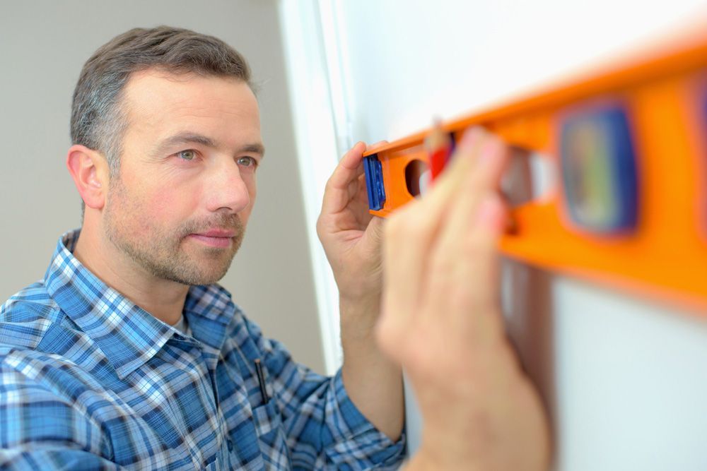 A Man is Measuring a Wall With a Level — A. Webber Building in Culburra, SA