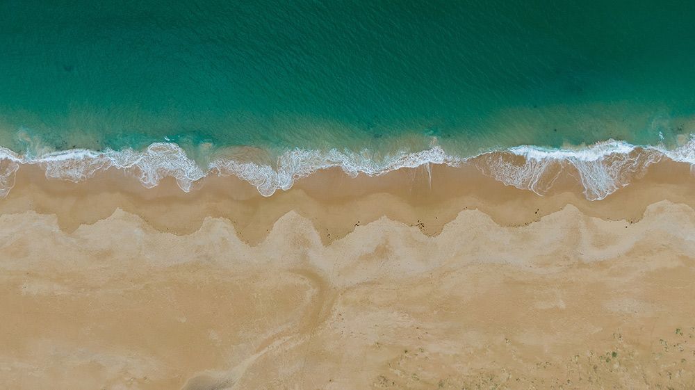 An Aerial View of a Beach With Waves Crashing on the Sand — A. Webber Building in Culburra, NSW