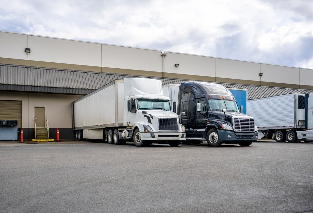 Two Semi Trucks Are Parked in Front of a Warehouse — Bowen Mechanical & Haulage in Bowen, QLD