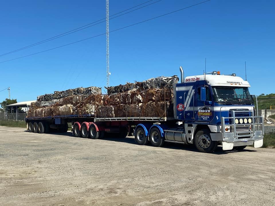 A Blue and White Semi Truck With a Trailer Full of Logs — Bowen Mechanical & Haulage in Bowen, QLD