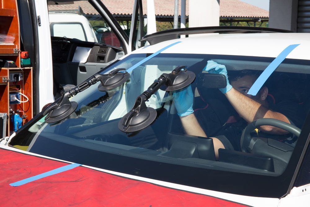 A Man is Installing a Windshield on a Car — Bowen Mechanical & Haulage in Bowen, QLD
