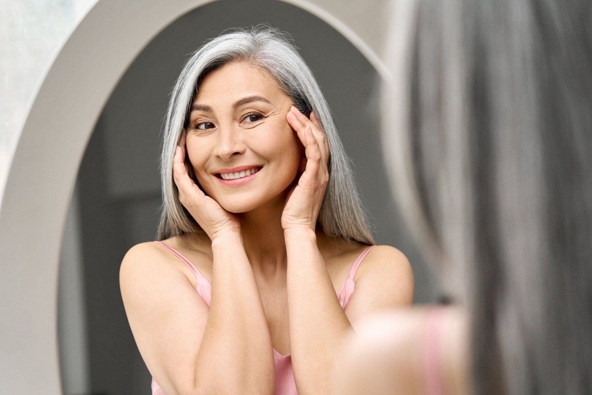 Woman smiling in mirror admiring her skin