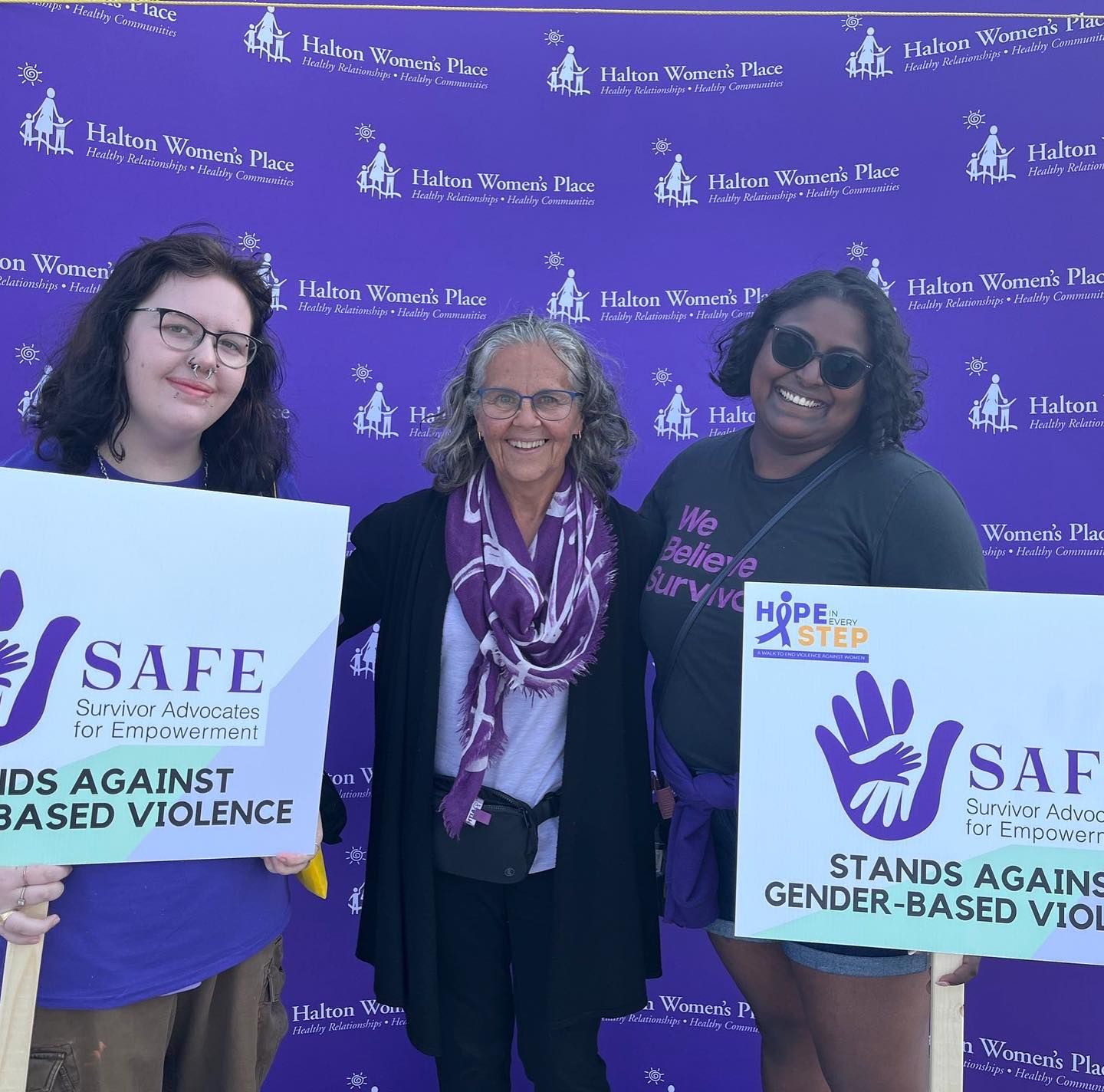 A woman is sitting on a bed wearing a white tank top and green shorts.