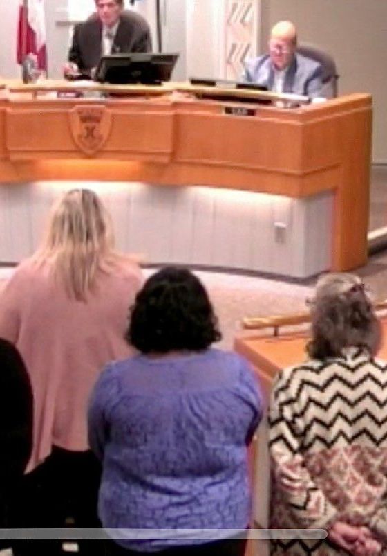 A group of people are sitting in front of a podium with the letter x on it.