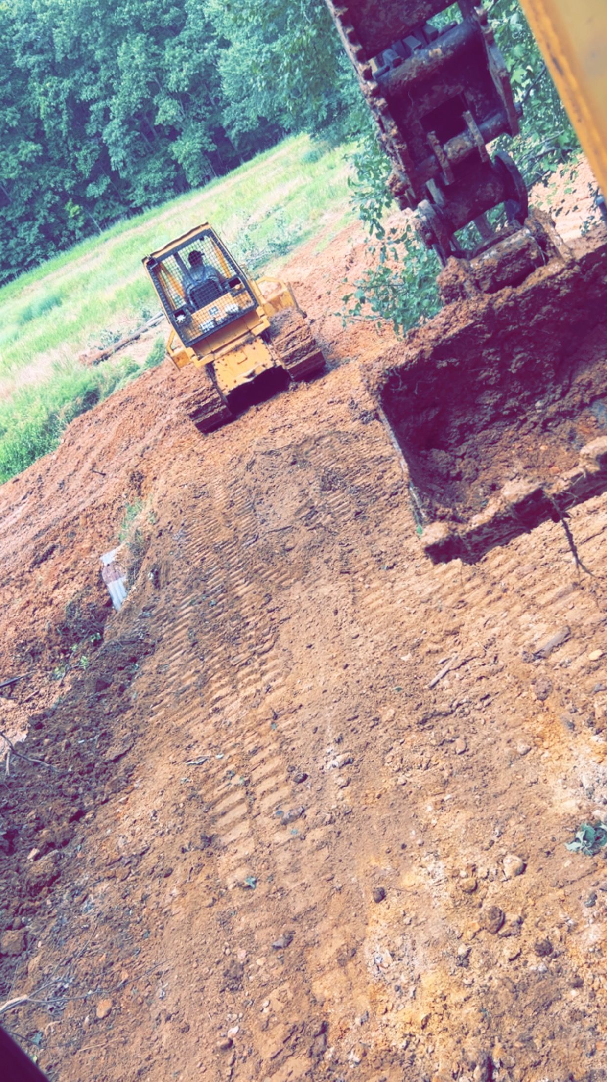 A couple of bulldozers are driving down a dirt road.