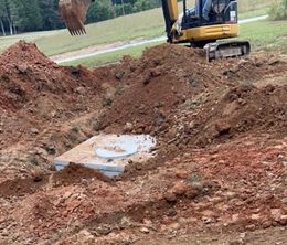 A yellow excavator is digging a hole in the dirt.