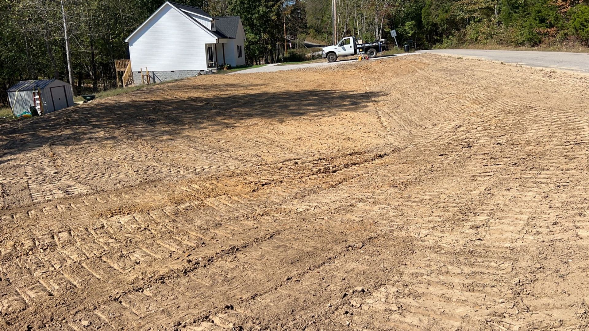 A dirt field with a white house in the background.