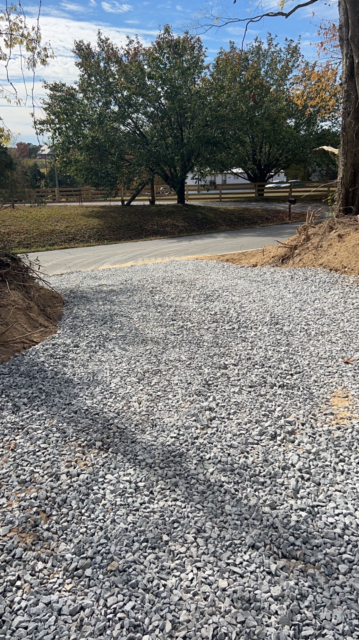 A gravel driveway with trees in the background.