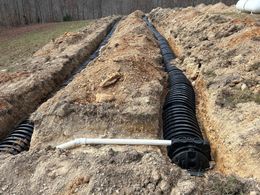 A septic system is being installed in a dirt field.