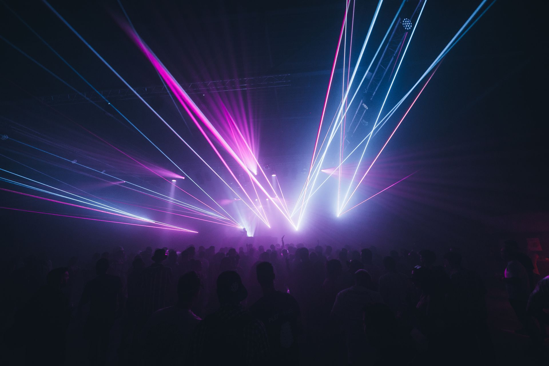A crowd of people are watching a laser show at a concert.