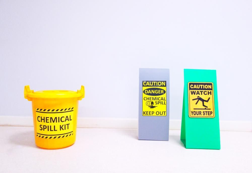 A Yellow Chemical Spill Kit Is Sitting Next to Two Caution Signs — Envirokleen Solutions In Slade Point, QLD