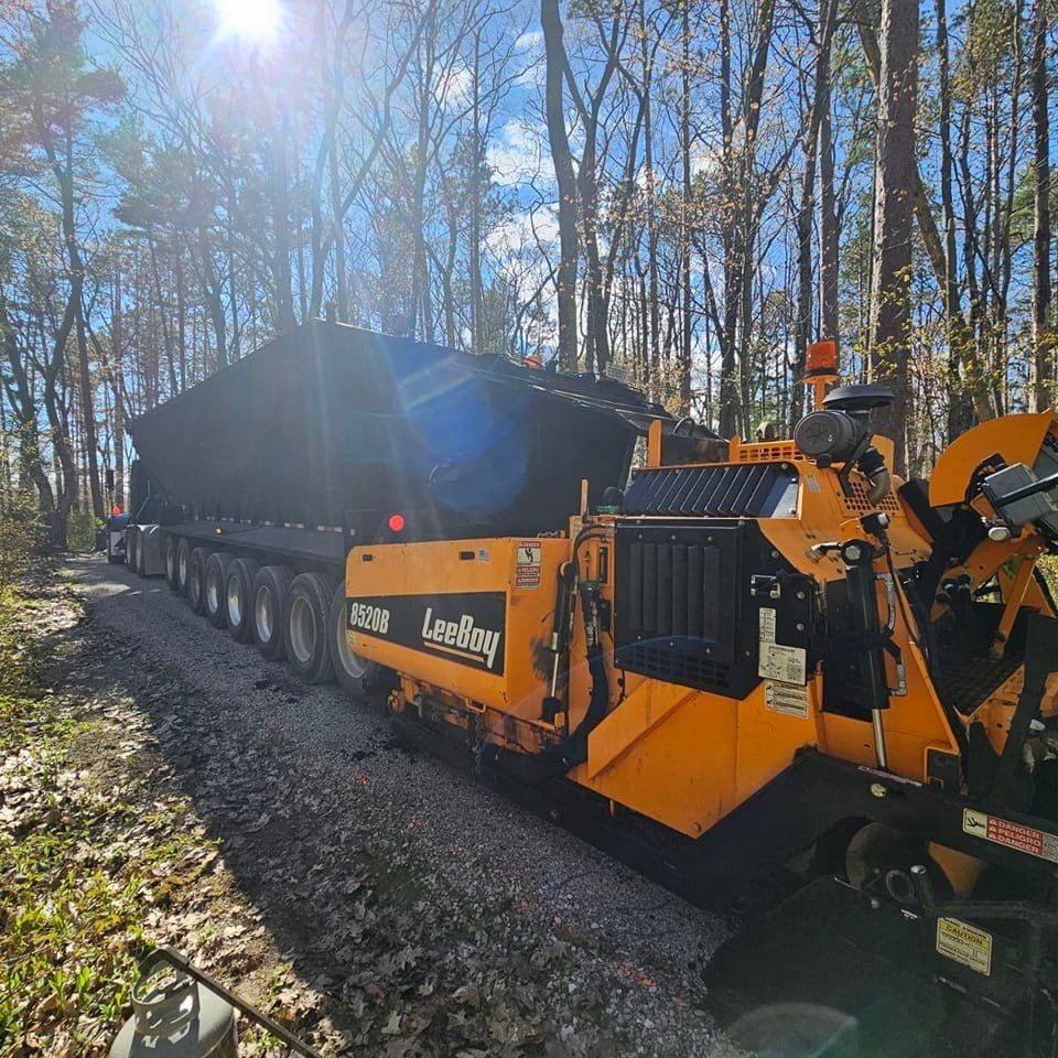 A large yellow truck is driving down a dirt road.