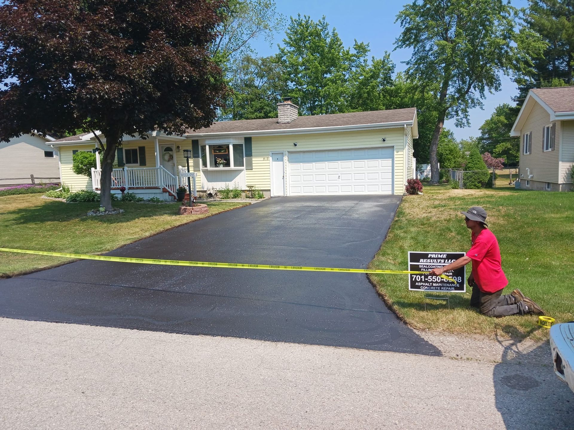 A man in a red shirt is measuring a driveway in front of a house