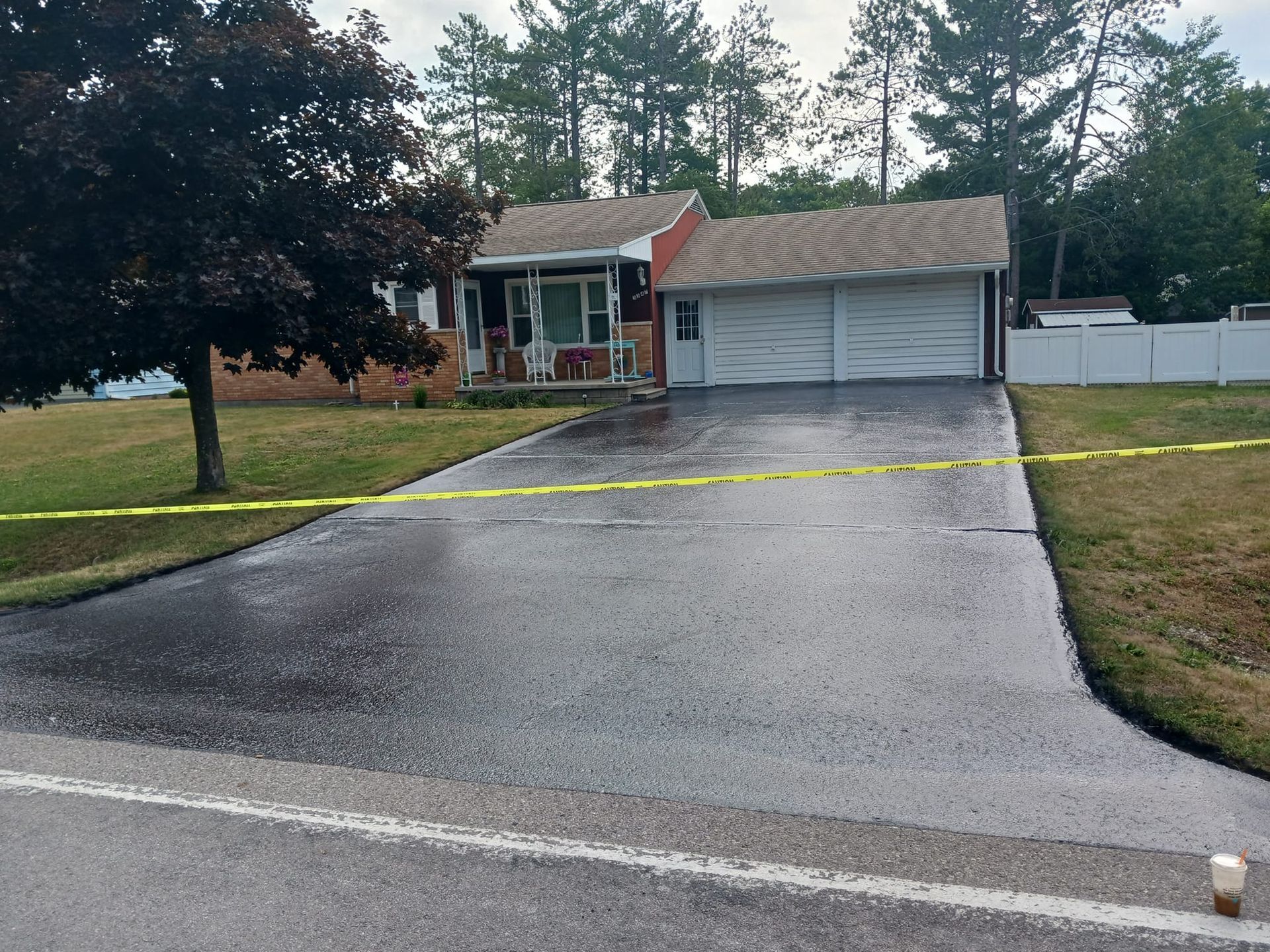 A driveway leading to a house with yellow tape around it.
