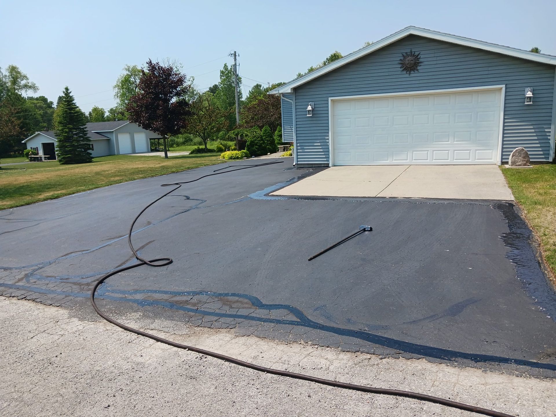 A hose is being used to clean a driveway in front of a garage