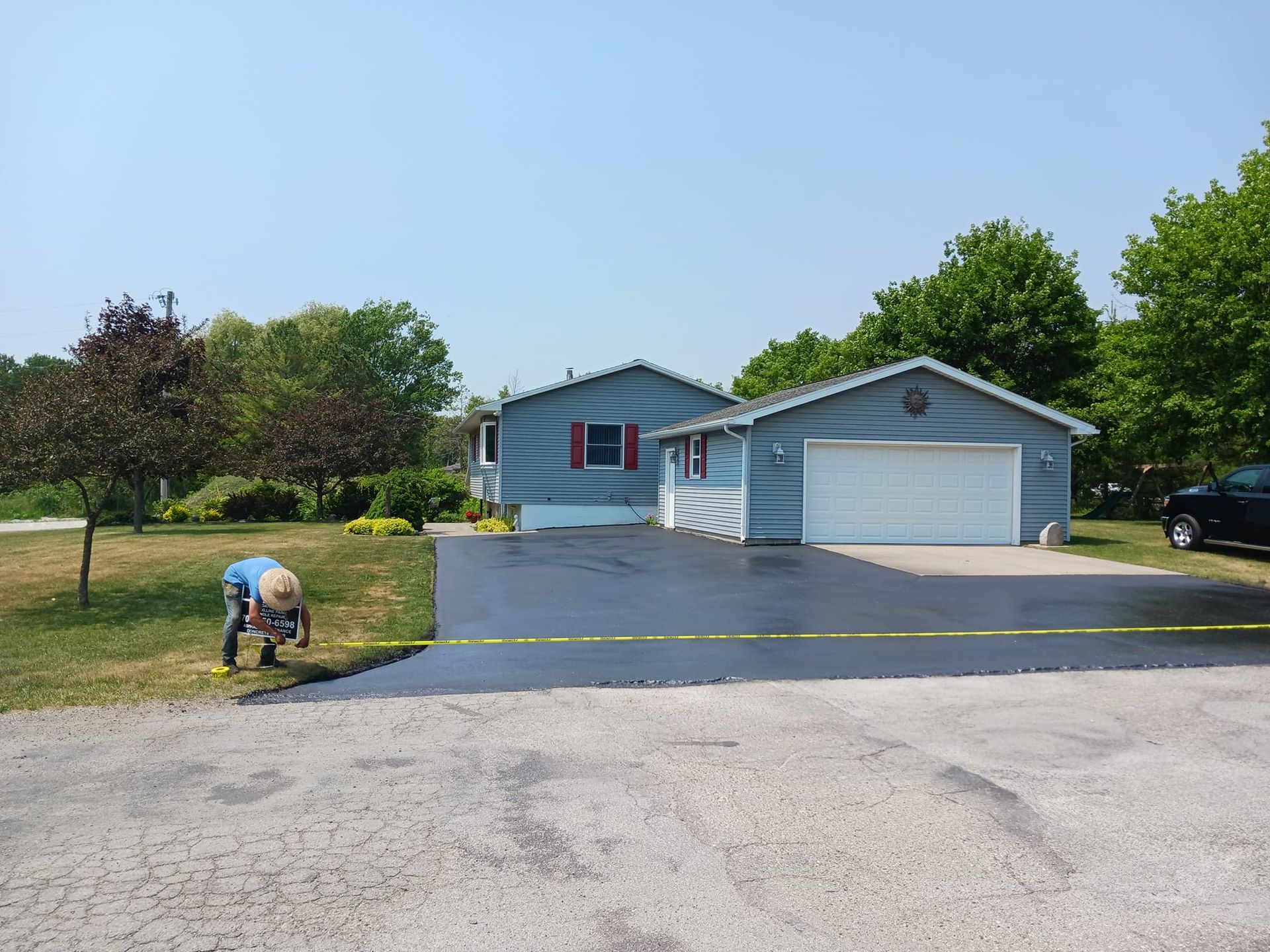 A man is working on a driveway in front of a house.