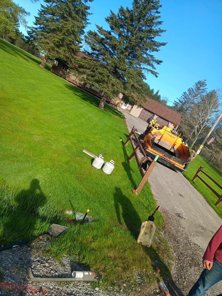 A man is walking down a dirt road next to a fence and a tractor.