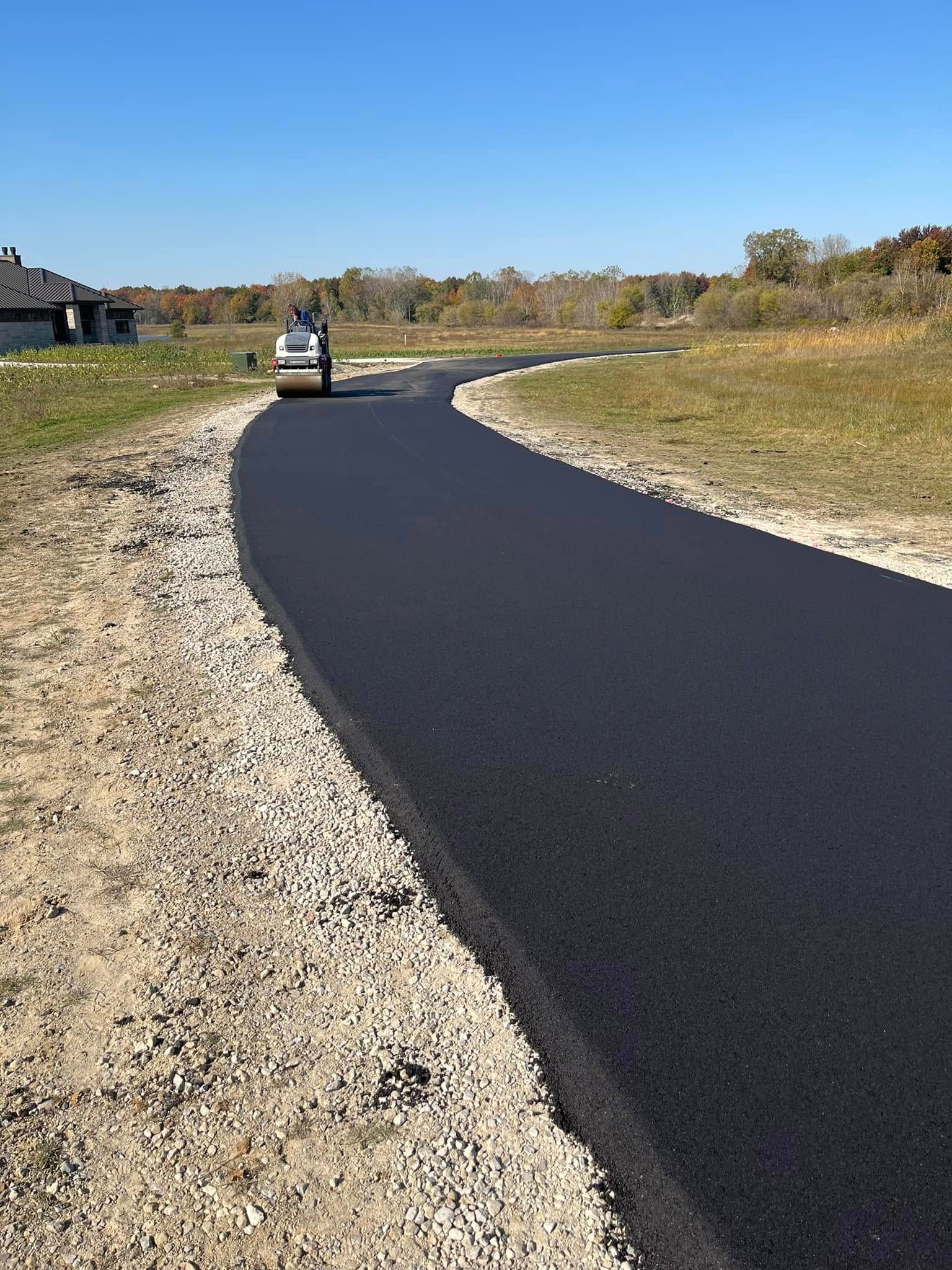 A car is driving down a newly paved road.
