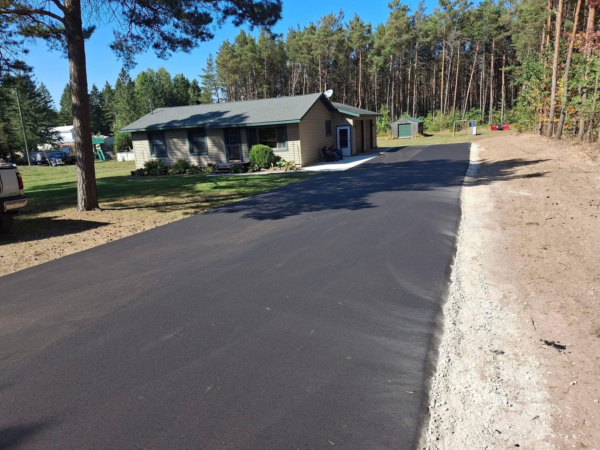 A driveway leading to a house in the woods.
