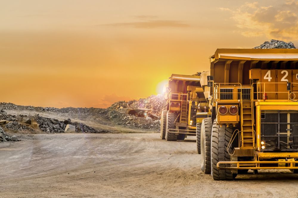 A Row of Dump Trucks Are Parked in A Dirt Field at Sunset — PBC Compliancing Pty Ltd in Dysart, QLD