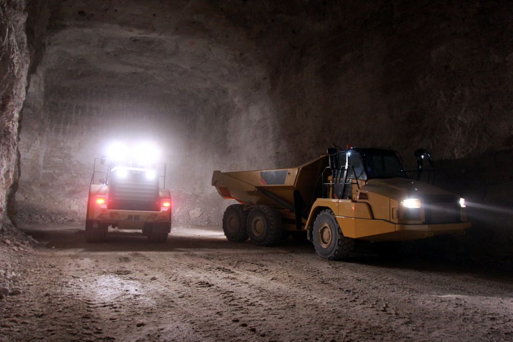 Two Trucks Are Driving Down a Dirt Road in A Tunnel — PBC Compliancing Pty Ltd in Moranbah, QLD