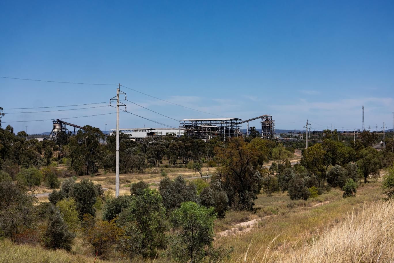 There is a Large Building in the Distance Surrounded by Trees and Power Lines — PBC Compliancing Pty Ltd in Moranbah, QLD