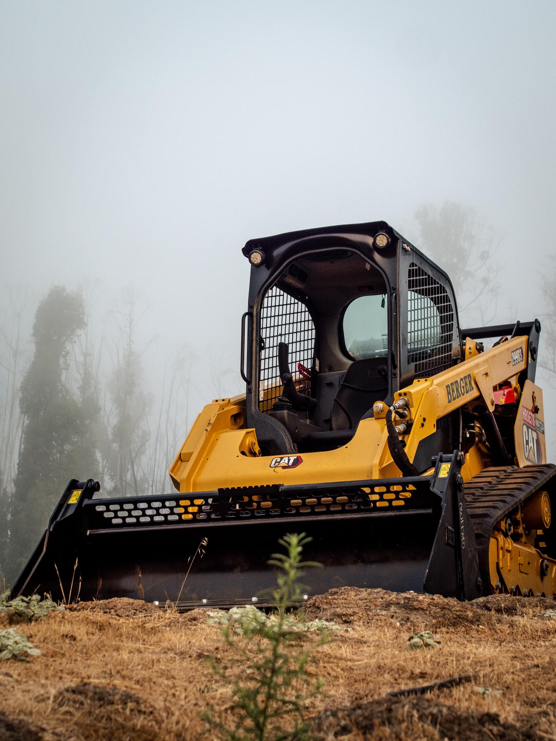 Yellow Caterpillar Skid Steer in A Foggy Outdoor Environment — PBC Compliancing in Paget, QLD